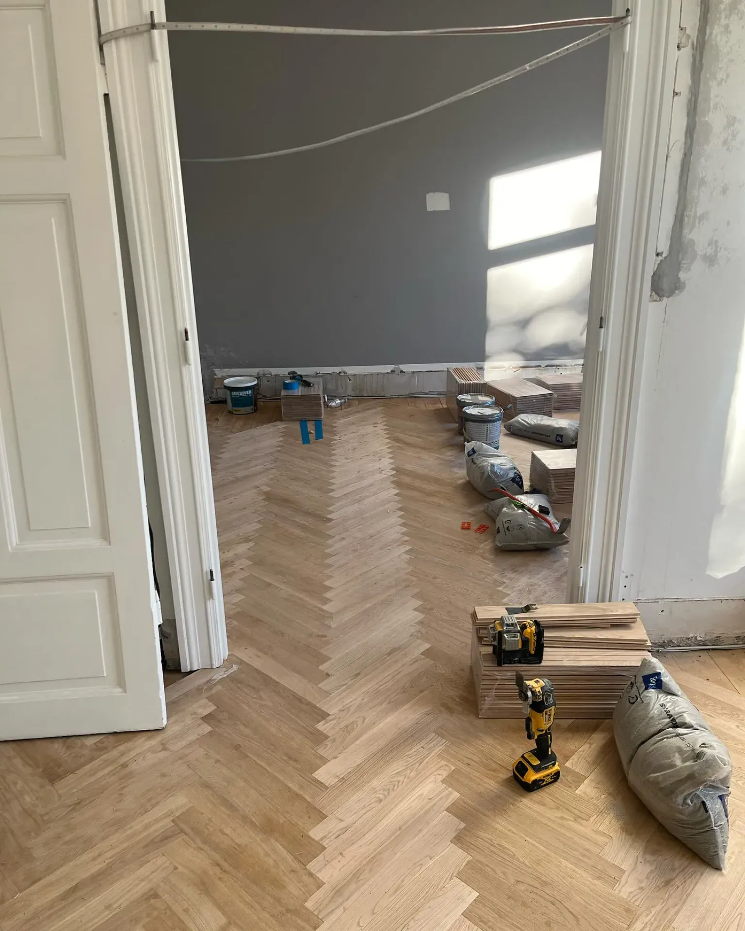 Nyt trægulv under installation i et rum med værktøj og byggematerialer.