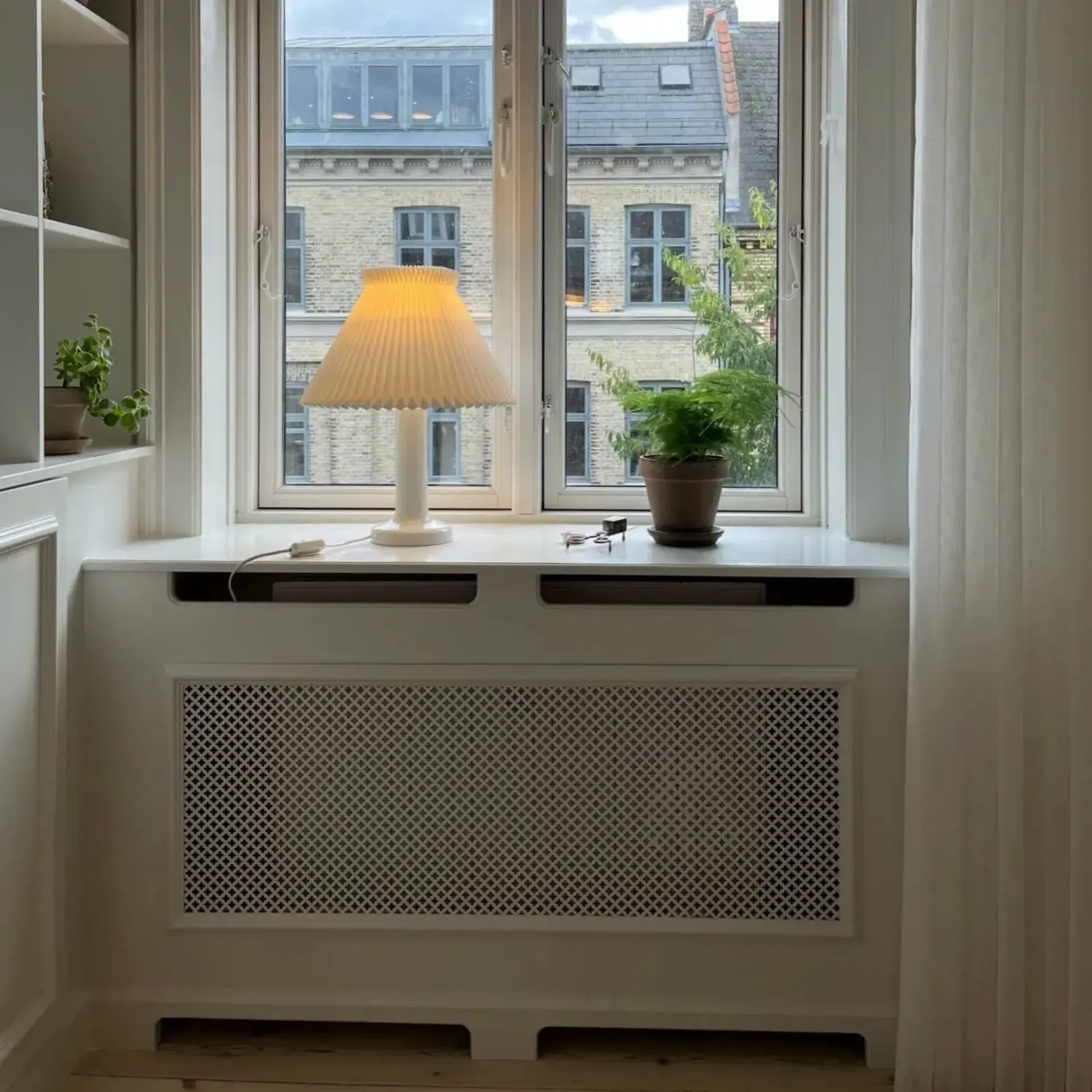 Vindueskarm med lampe og plante i stue.
