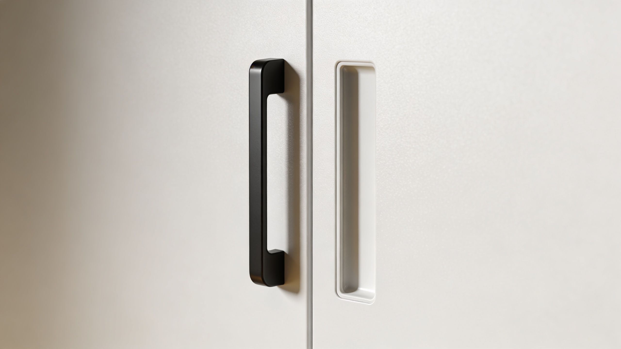 Et nærbillede af to forskellige dørhåndtag på et lyst skab med en moderne og minimalistisk stil.